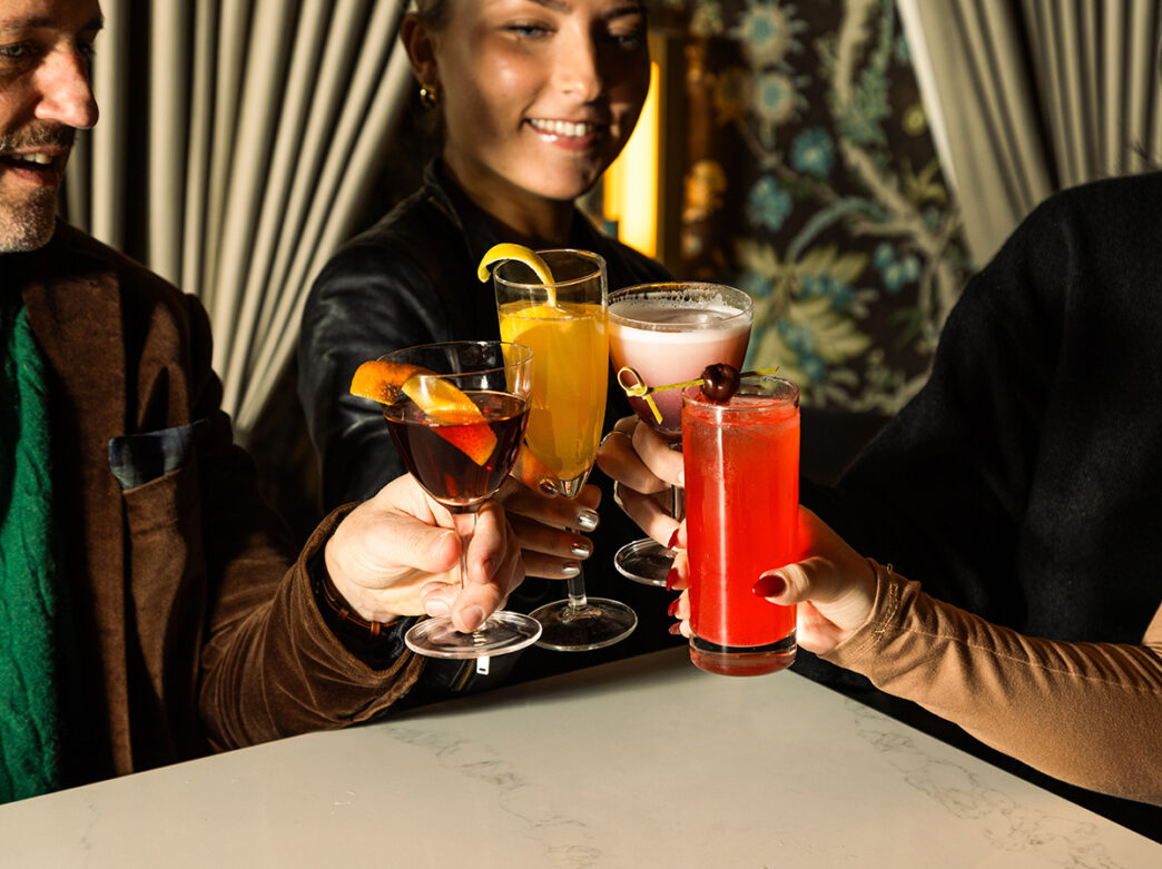 People people cheers orange, pink and red cocktails at 48 Record Bar in Philadelphia.