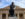 A close-up view of Rodin's "The Thinker" sculpture, a bronze figure seated in deep contemplation with his chin resting on his hand. The tan facade of the Rodin Museum can be seen in the background.