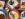 Overhead spread of dishes from African Small Pot in Philadelphia, featuring whole fried fish with plantains, stewed greens with fufu, shrimp in dark sauce with rice, grilled chicken over rice, sautéed vegetables, and brightly colored woven placemats on a wooden table.