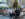 A group of people enjoy drinks and socialize at outdoor tables in Dilworth Park in downtown Philadelphia, with tall skyscrapers and trees visible in the background.