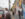 A guide speaks to a group of people gathered on a city sidewalk in front of a colorful mural depicting smiling figures, during a walking tour in the Centro de Oro neighbhorhood.