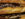 A detail image of a cheesesteak on a seeded roll. Melted cheese drips over sliced beef.