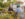 Two people sit at an outdoor table at Liberty Beer Garden in Philadelphia, chatting over drinks surrounded by yellow flowers and string lights in a relaxed garden setting.
