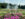 Fountains shoot water into the air above a grand formal garden at Longwood Gardens, framed by pink flowers in the foreground and lush trees in the background.