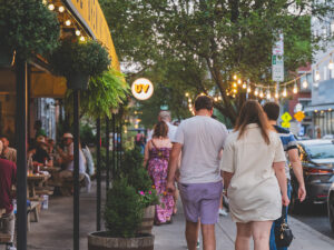People walk away from the camera on a lively sidewalk in Philadelphia's Northern Liberties neighborhood, passing outdoor diners.