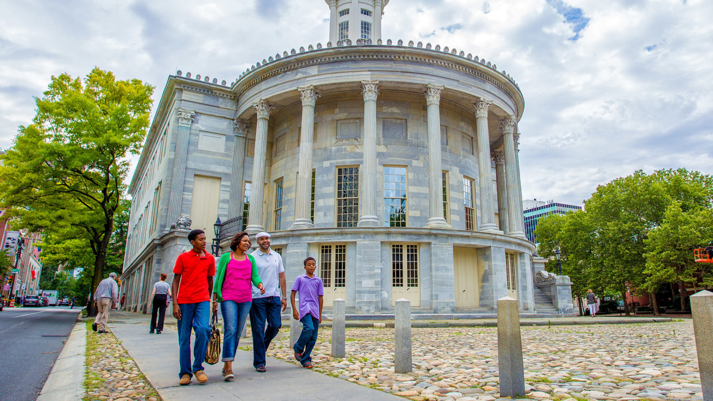 A family walks past the Merchants Exchange building in Old City Philadelphia