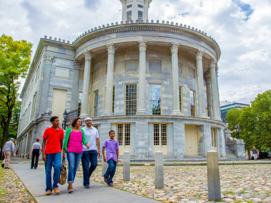 A family walks past the Merchants Exchange building in Old City Philadelphia