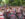 A colorful drumline performs during the Philadelphia Pride March as musicians in rainbow-trimmed outfits march down a tree-lined street. Crowds gather along the route waving pride flags and cheering during the outdoor celebration.