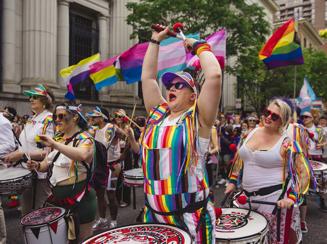 Members of the energetic, rainbow-draped drum line lead the Philly Pride March through the city streets.