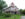 A Victorian mansion with a red roof and wrap around porch set in a green lawn.