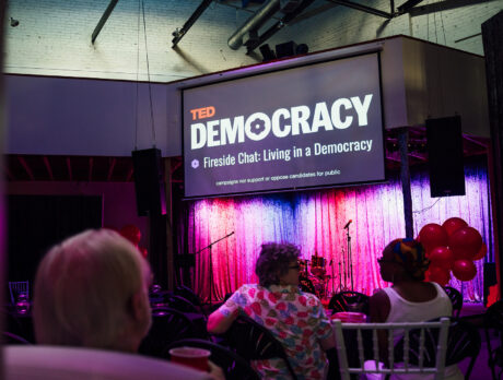 A screen shows the TED Democracy Talk in Philadelphia at a community watch party