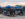 Visitors gather at picnic tables beneath blue umbrellas at Union Yards, an outdoor tailgate and event space adjacent to the Philadelphia Union's Stadium, Subaru Park, in Chester, Pennsylvania.