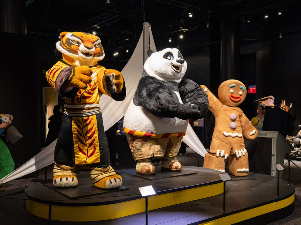 Large character costumes, including a tiger, panda and gingerbread figure, stand on a display inside the Universal Theme Parks exhibition gallery.