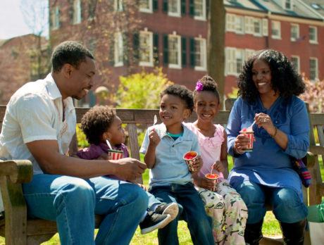 A family of five enjoys cups of water ice on a bench in Washington Square